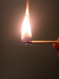 Close-up of hand holding lit candle in the dark