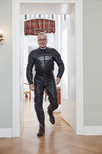 Senior man in motorcycle suit at home