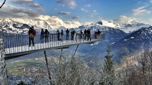 Tourists at observation point against snow covered mountains