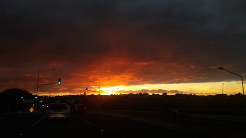 Cars on road against cloudy sky