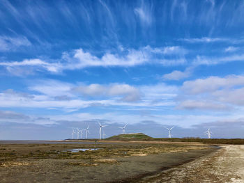 Scenic view of road with windturbines against sky