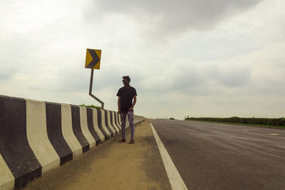 Rear view of man standing on road against sky