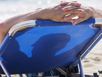 Rear view of man relaxing on lounge chair at beach