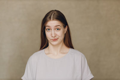 Portrait of young woman standing against black background