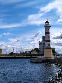 Lighthouse by sea against sky