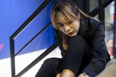 Close-up of thoughtful businesswoman sitting against railing