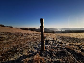 Wooden posts on field against clear sky