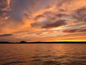 Scenic view of sea against dramatic sky during sunset