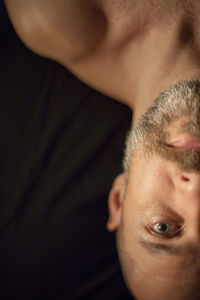 High angle portrait of shirtless man lying on bed at home