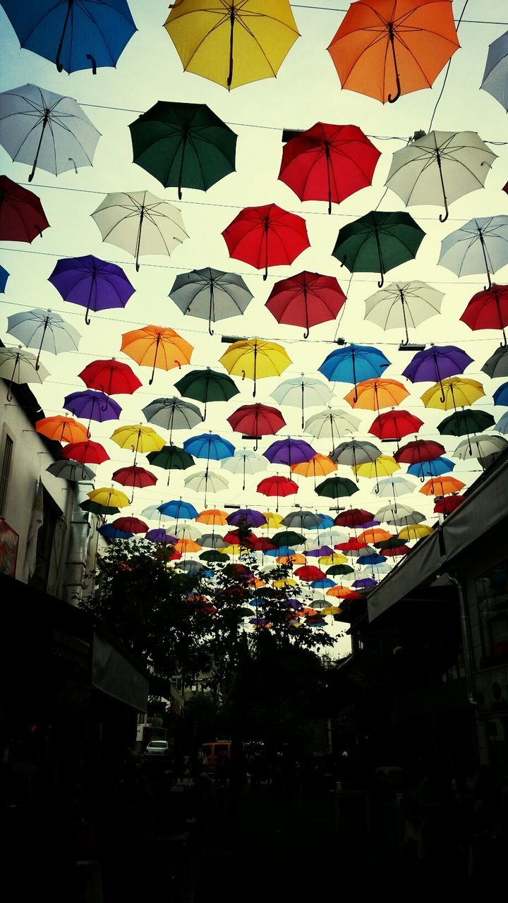 multi colored, architecture, built structure, building exterior, decoration, low angle view, hanging, city, illuminated, variation, lighting equipment, celebration, colorful, abundance, in a row, city life, umbrella, sky, no people, flag