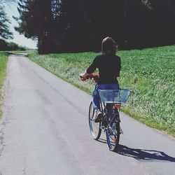 Rear view of man riding bicycle on road