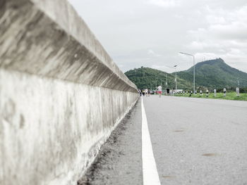 Surface level of road by wall against sky