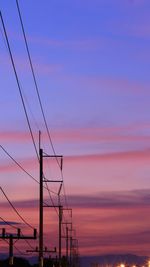 Low angle view of silhouette electricity pylon against romantic sky