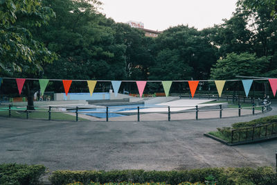 Empty chairs by swimming pool in city against sky