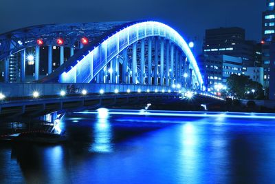 Illuminated bridge against blue sky at night