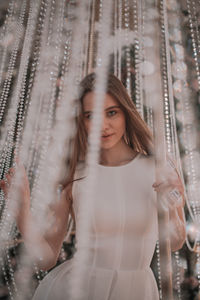 Portrait of young woman standing in curtain