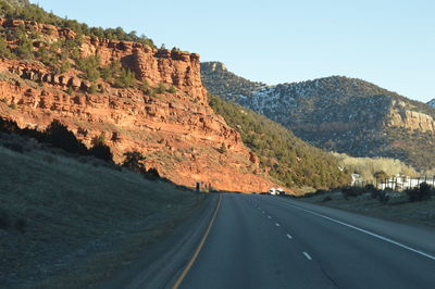 Road by mountains against clear sky