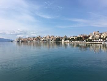 Buildings by sea against blue sky