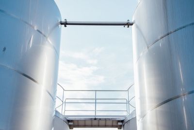 Low angle view of storage tanks against sky at factory