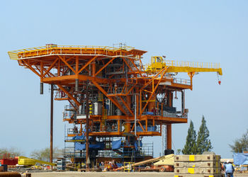 Low angle view of crane at construction site against sky