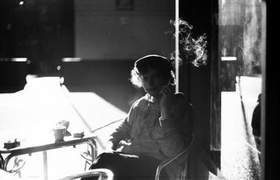 Young man smoking on wall at night