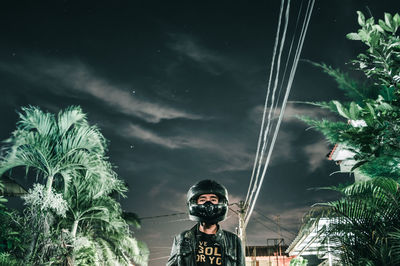 Low angle view of man in helmet standing against sky at night