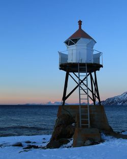 Lighthouse on sea against clear sky