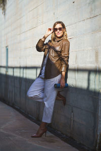 Full length of young woman standing against wall