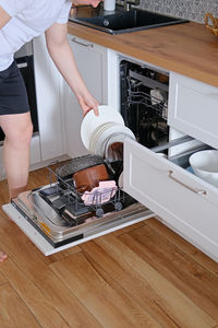 Man taking clean dishes out of dishwasher