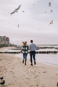 Close up of couple running near the sea and looking to each other.