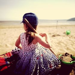 Woman holding umbrella on beach against sky