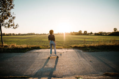 Rear view of man walking on road against sky