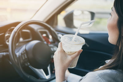 Woman drinking coffee while driving car
