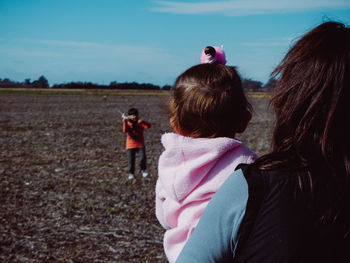 Rear view of woman with daughter and son standing on land