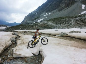 Man with bicycle on mountain against sky