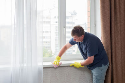 Side view of man looking through window