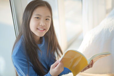 Portrait of girl with book at home