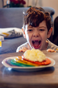 Portrait of boy with pancakes and cream in plate