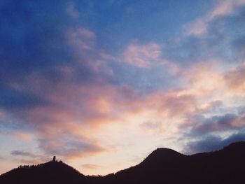 Scenic view of mountains against cloudy sky at sunset