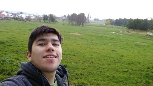 Portrait of boy smiling on field against clear sky