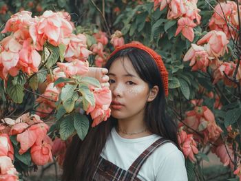 Portrait of young woman standing by flowering plants