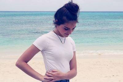 Teenage girl standing on beach against sea