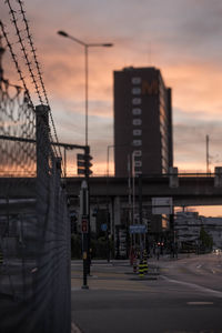 Street by buildings against sky at sunset