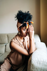 Portrait of young woman sitting on sofa at home