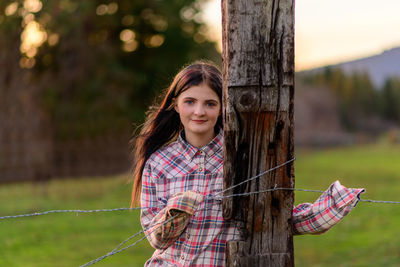 Portrait of young woman grabbing barbed wire fence