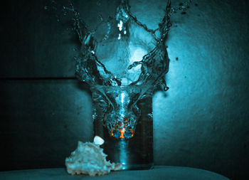 Close-up of water splashing on glass table against wall