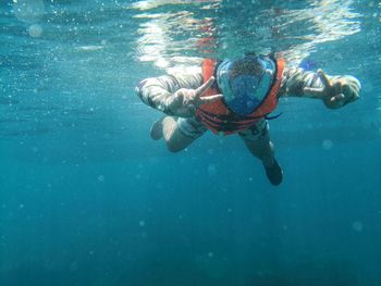 Boy showing peace sign while swimming in sea