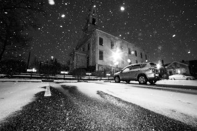 Cars on illuminated street in city at night during winter