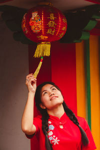 Full length of smiling woman standing against red wall