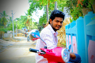 Young man looking away while sitting on bike road out side